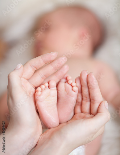 Photo: mother hands holding small baby's feet mother hands holding small baby's feet