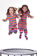 Two young girls jumping on a trampoline