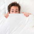 Scared man hiding in bed