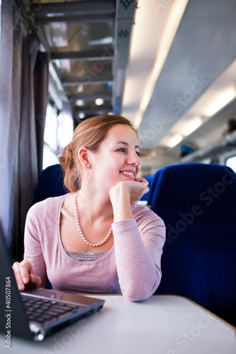Photo: Young woman using her laptop computer while on the train Young woman using her laptop computer while on the train