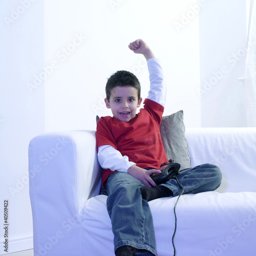 Foto: Boy raising his hand while playing with video game console Boy raising his hand while playing with video game console