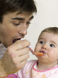 Father feeding baby girl