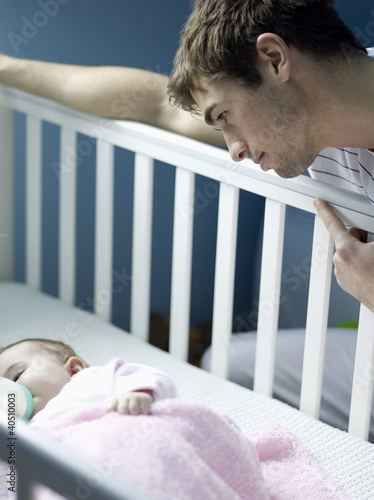 Photo: Father watching baby girl sleeping in the crib Father watching baby girl sleeping in the crib