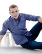Portrait of a casual young satisfied man sitting relaxed. on whi