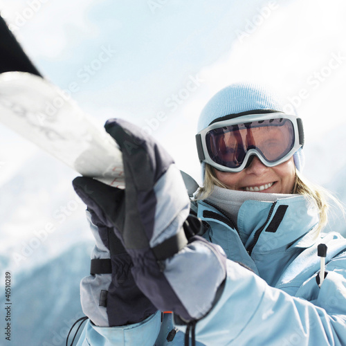 Foto: Woman in ski goggles holding snowboard Woman in ski goggles holding snowboard