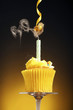 A cupcake with blown out candle and a frog hanging from a streamer