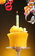 Close-up of a cupcake with a candle and streamers