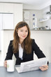 Businesswoman reading newspaper while having coffee