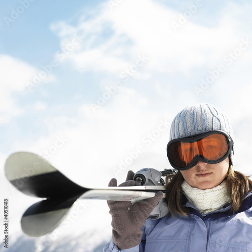 Photo: Woman in ski goggles holding skis Woman in ski goggles holding skis