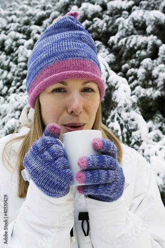 Photo: Woman drinking hot beverage, standing outdoor Woman drinking hot beverage, standing outdoor