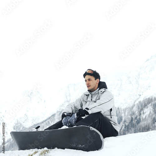 Photo: Male snowboarder sitting alone Male snowboarder sitting alone
