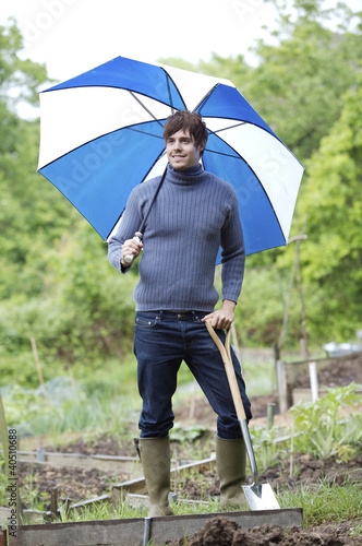Photo: Man with umbrella holding long-handled spade Man with umbrella holding long-handled spade
