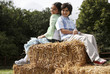 Boy and girl sitting on haystacks