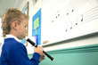 Boy playing the recorder by refering to music notes on the whiteboard