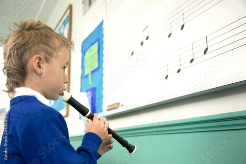 Photo: Boy playing the recorder by refering to music notes on the whiteboard Boy playing the recorder by refering to music notes on the whiteboard