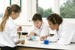 Woman assisting boy and girl in their science experiment