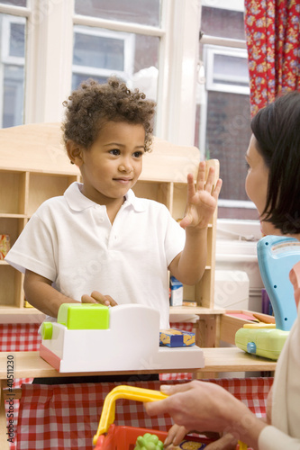 Photo: Boy gesturing while playing with toys, woman carrying basket Boy gesturing while playing with toys, woman carrying basket