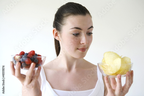 Photo: Woman holding a bowl of berries and chips in each hand Woman holding a bowl of berries and chips in each hand