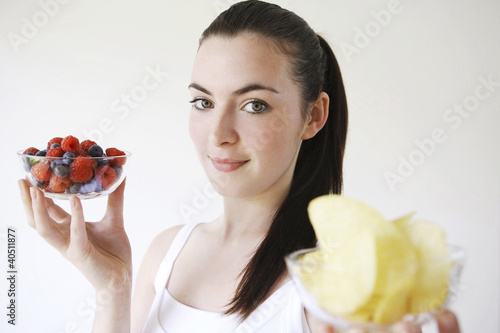 Photo: Woman holding a bowl of berries and chips in each hand Woman holding a bowl of berries and chips in each hand
