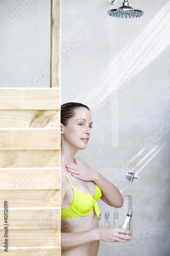 Photo: Woman applying bath liquid on body while taking a shower Woman applying bath liquid on body while taking a shower