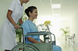 Nurse pushing woman on wheelchair, woman holding a vase of flowers