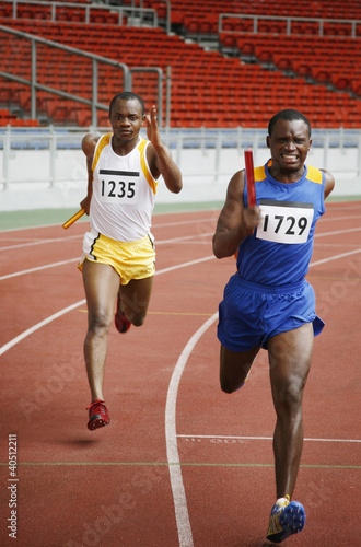 Photo: Men running while holding baton Men running while holding baton
