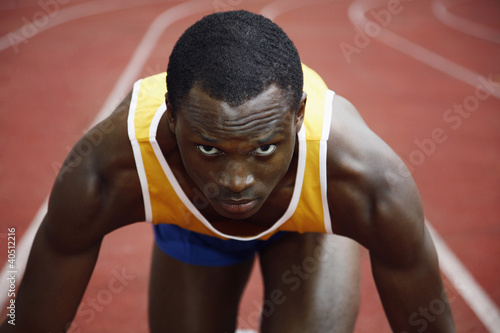 Foto: Man in starting position on running track Man in starting position on running track