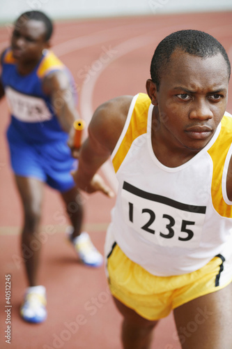 Photo: Men passing baton in relay race Men passing baton in relay race