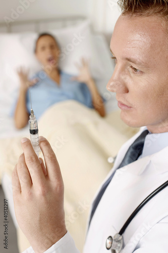 Photo: Doctor holding syringe, patient screaming Doctor holding syringe, patient screaming