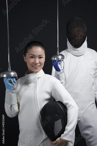 Photo: Man and woman in fencing suits posing for the camera Man and woman in fencing suits posing for the camera