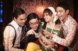 Woman and three men laughing after reading text message on cellphone