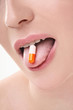 Woman showing pill on her tongue