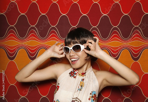 Photo: Woman smiling while adjusting her sunglasses Woman smiling while adjusting her sunglasses