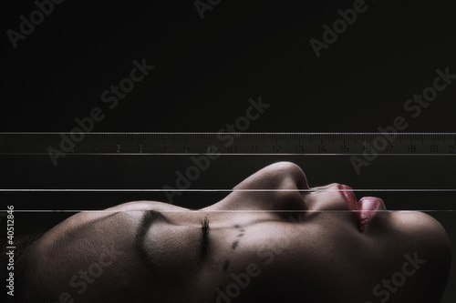 Photo: Woman with ruler against front of face Woman with ruler against front of face