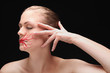 Woman with lipstick drawing on her face closing her eyes