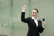 Businesswoman holding cellphone, shaking fist in victory