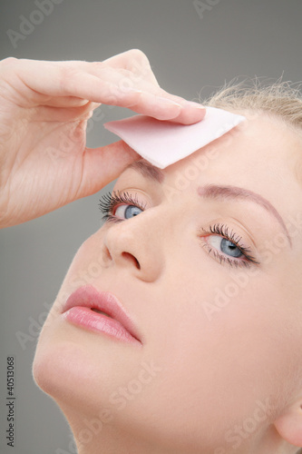 Photo: Woman wiping forehead with cotton pad Woman wiping forehead with cotton pad