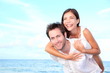 Happy beach couple piggyback Happy beach couple piggyback