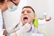 The dentist treats teeth of the man in the dental clinic