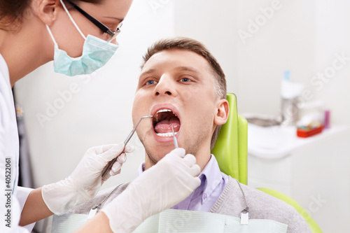 Foto: The dentist treats teeth of the man in the dental clinic The dentist treats teeth of the man in the dental clinic