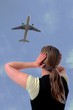 Frau mit Haenden an den Ohren und Flugzeug
