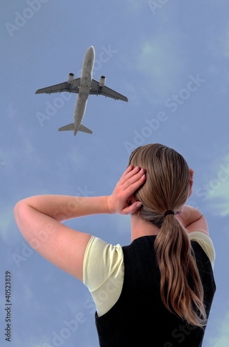 Foto: Frau mit Haenden an den Ohren und Flugzeug Frau mit Haenden an den Ohren und Flugzeug