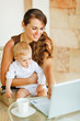 Photo: Young mother working with baby on laptop Young mother working with baby on laptop