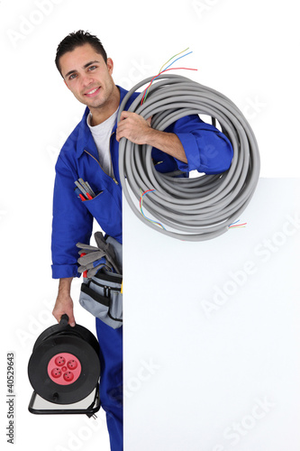 Photo: Electrician with extension cable stood by poster Electrician with extension cable stood by poster