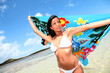 Woman at the beach holding sarong up in the air