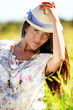 Gypsy girl with hat standing in field of wild flowers Gypsy girl with hat standing in field of wild flowers