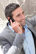 Businessman talking on mobile phone against wall