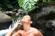 Beautiful girl showering in river under waterfall