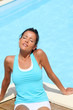 Brunette girl in fitness outfit relaxing by the pool