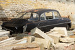 Old car wreck dumped in stones rubble